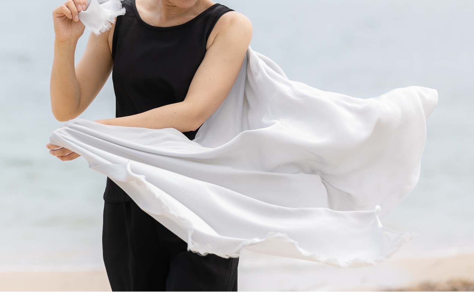 SOIE CÉLESTEの商品「黒のロングワンピース」を着用し、「シルクストール」を広げている女性の姿