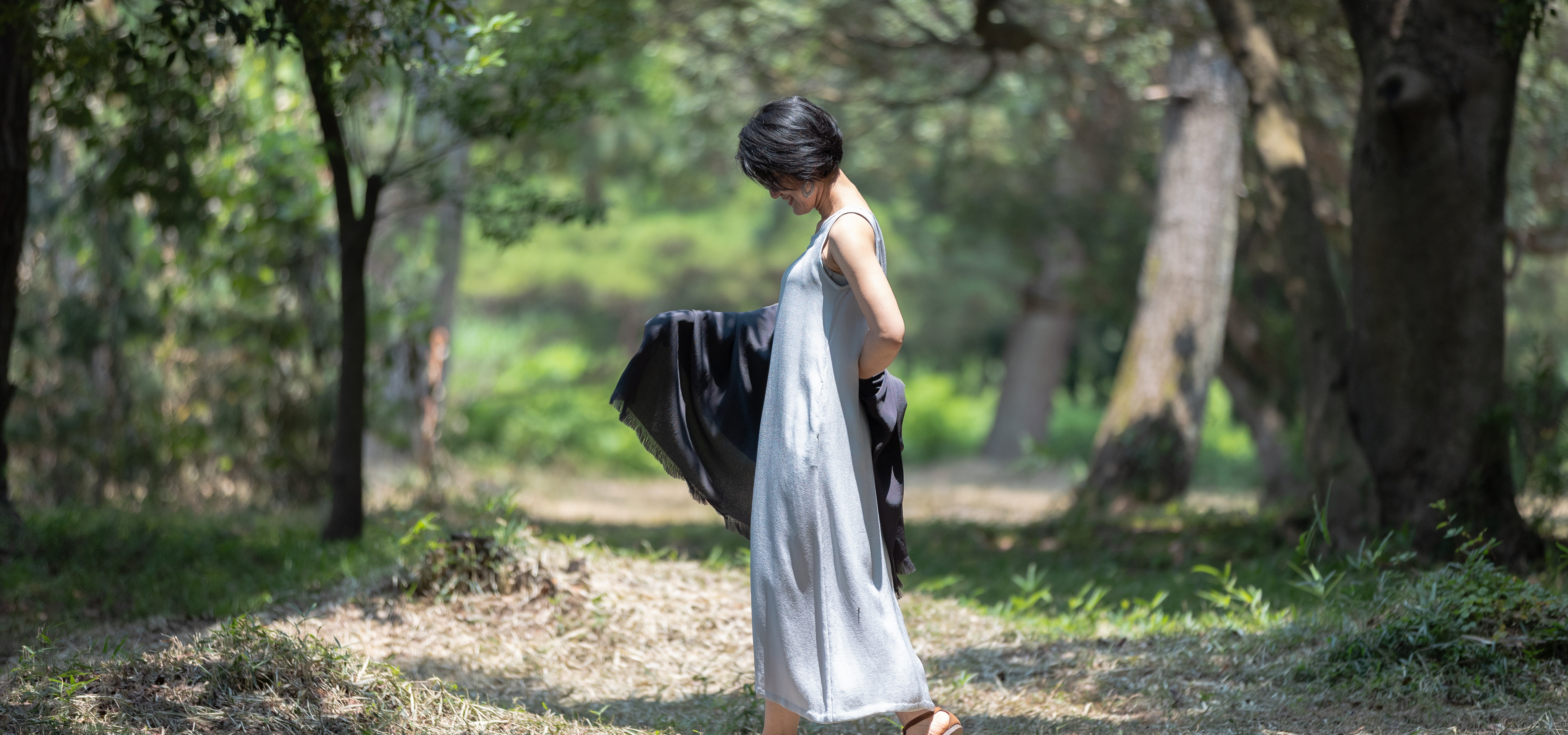森の中で、SOIE CÉLESTEの商品「グレーのワンピース」を着た女性